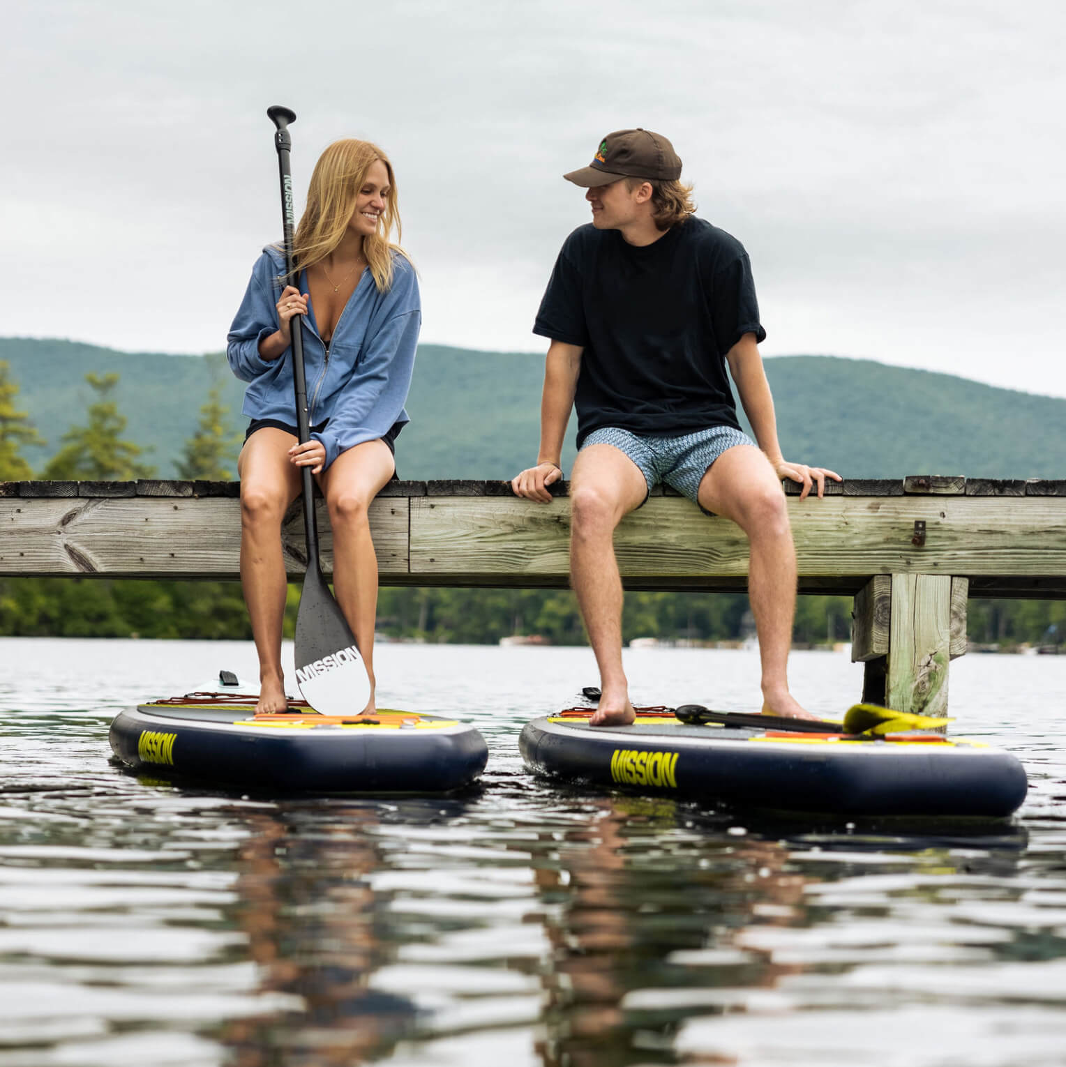 two people sitting on dock with TRIDENT Inflatable Touring SUPs