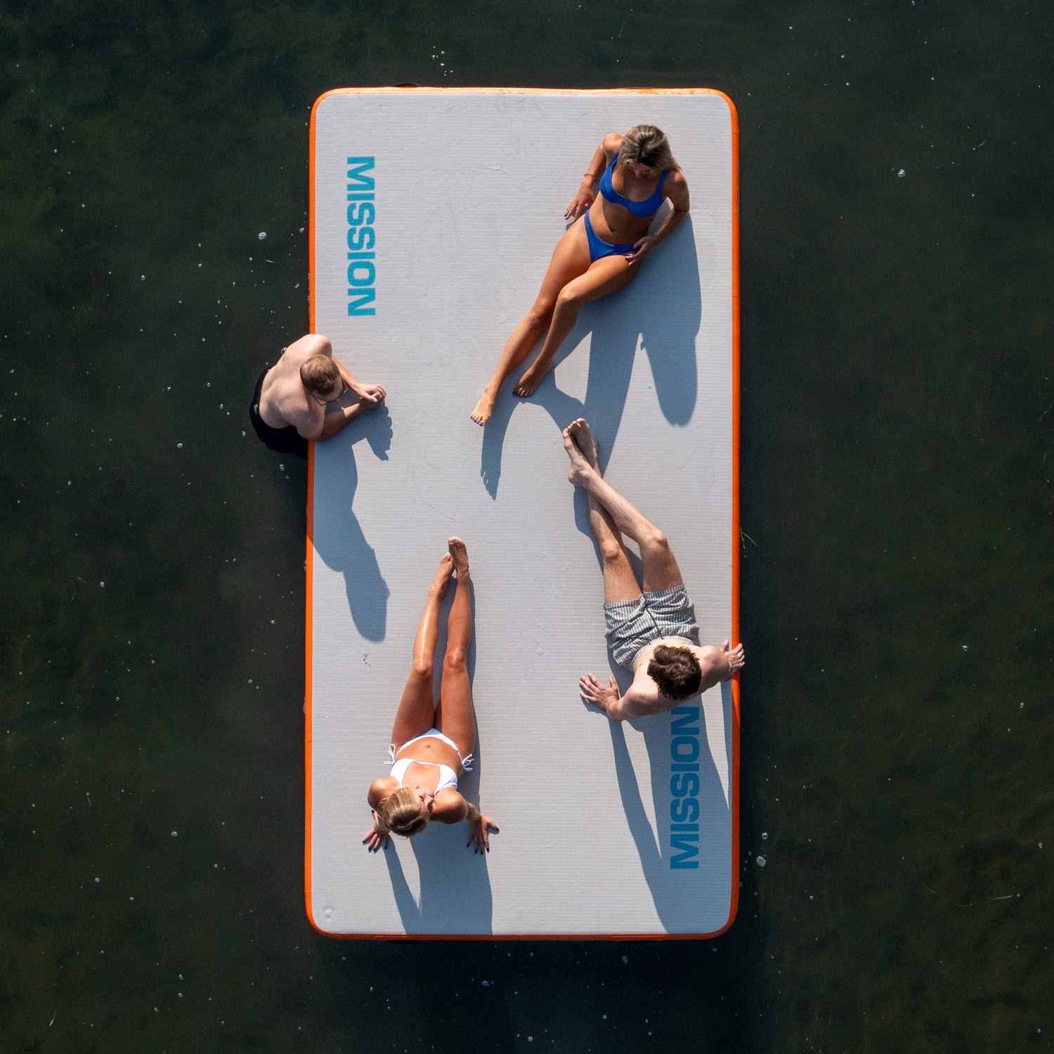 Four people laying on the inflatable water mat 