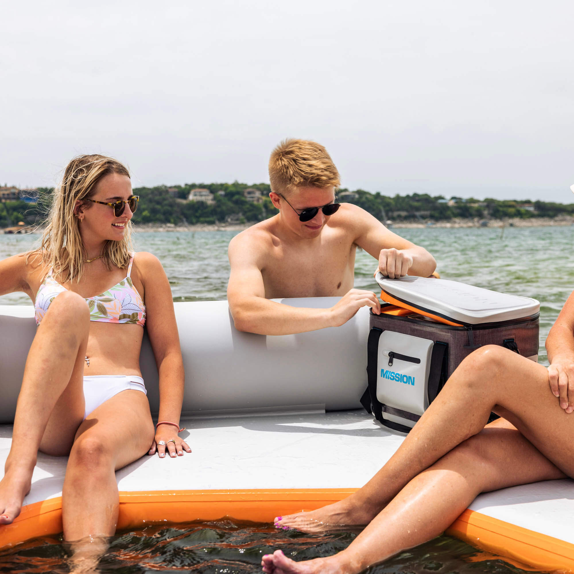 3 people on a floating mat with soft pack cooler