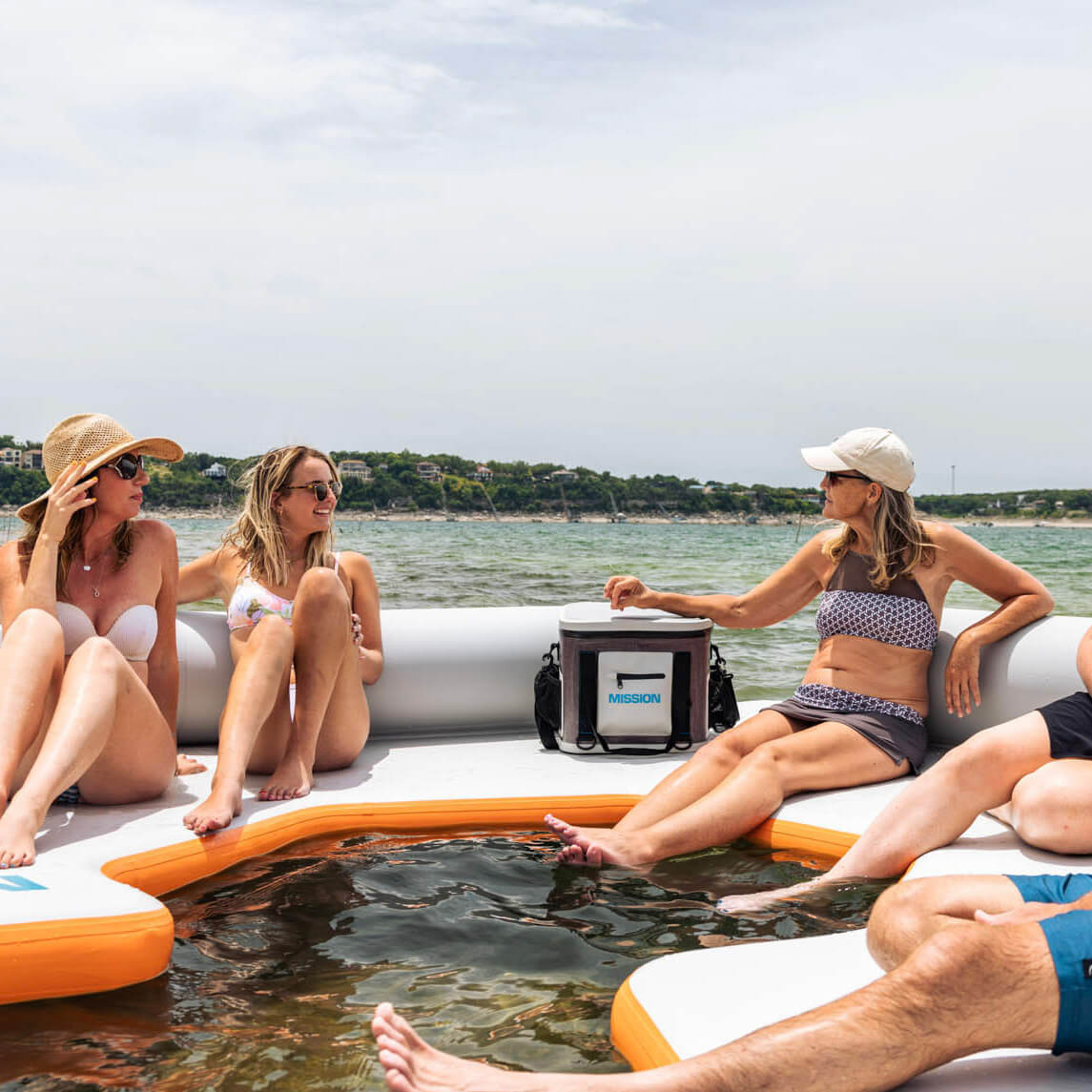 people on floating mat with boat cooler 