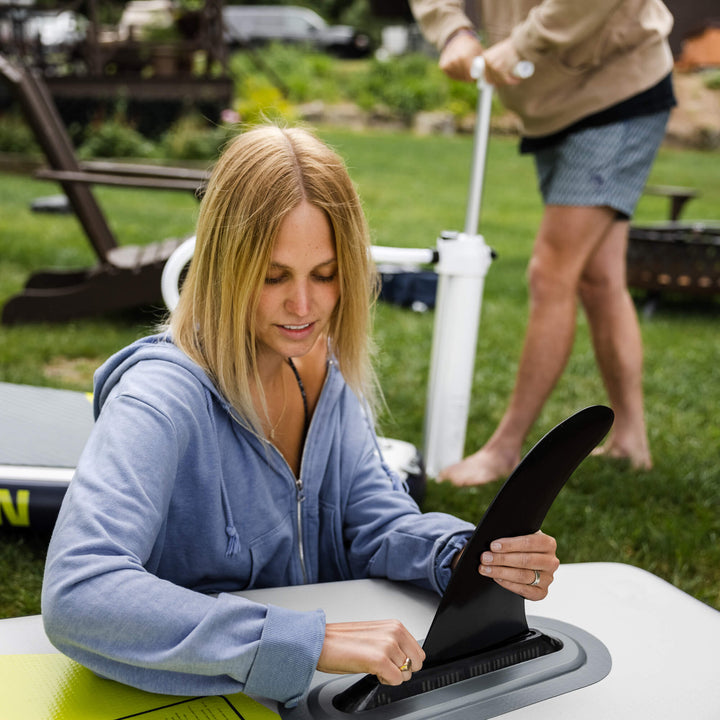 person putting fin on TRIDENT Inflatable Touring SUP