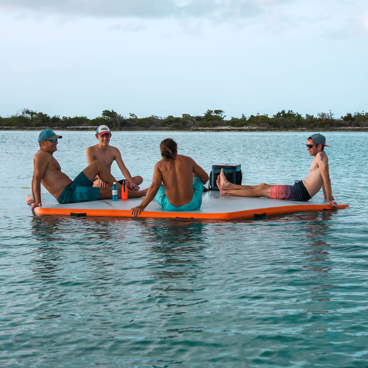Group of people sitting on REEF Mat in water